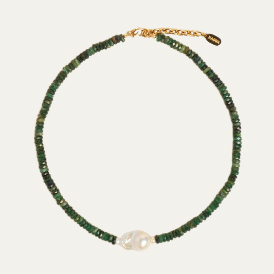 A delicate beaded necklace featuring small green faceted beads, a central white baroque pearl, and a gold-tone chain extender clasp with a brand tag.