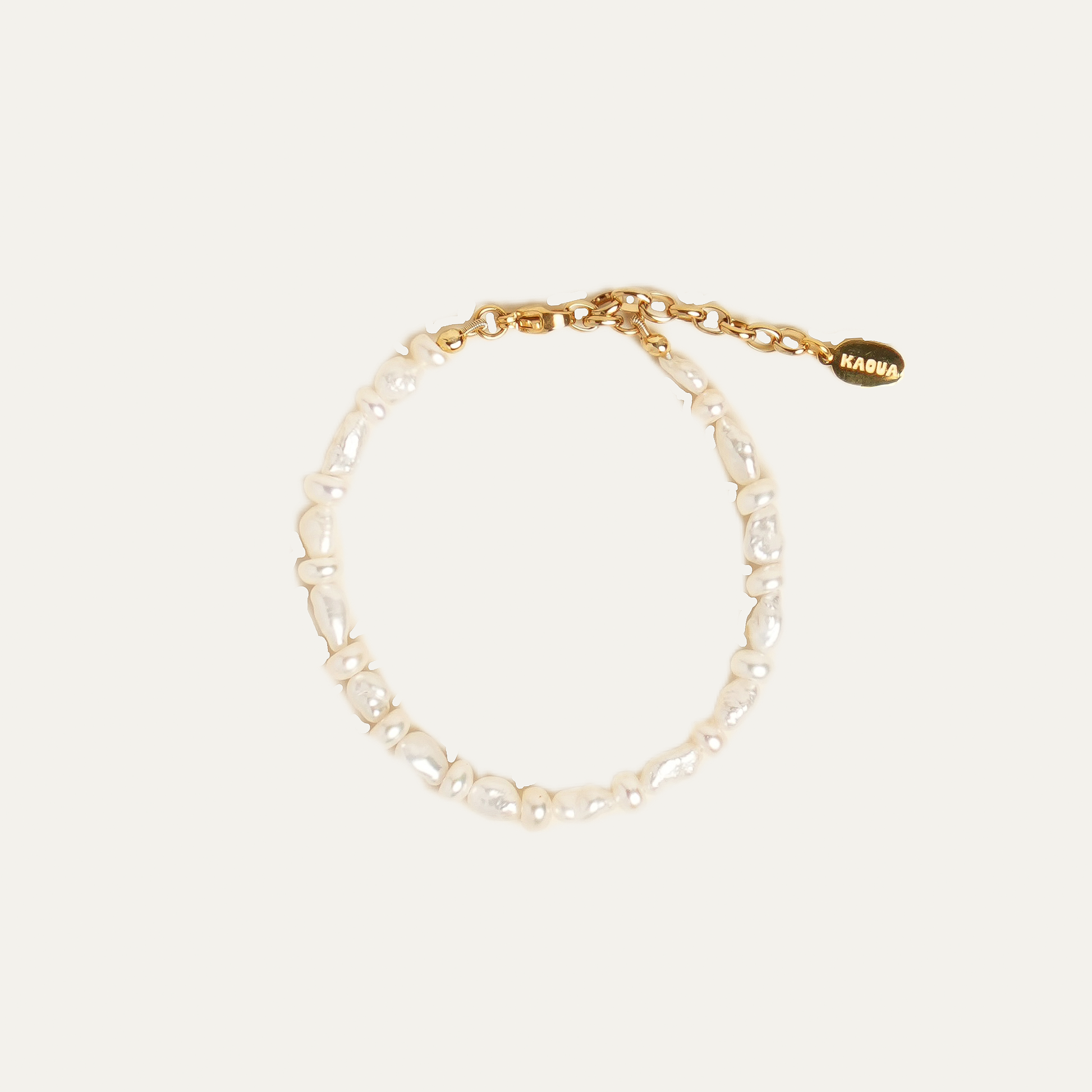 A delicate gold chain bracelet featuring irregular white baroque pearls, a lobster clasp, and an adjustable gold extender chain with a small gold tag engraved with the brand name 'KAOUA'.